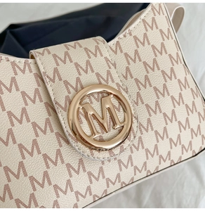Close-up of golden M-shaped metal clasp and monogram leather texture on retro handbag