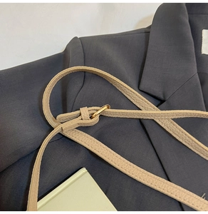 Close-up of beige lychee grain leather shoulder strap with gold adjustable buckle