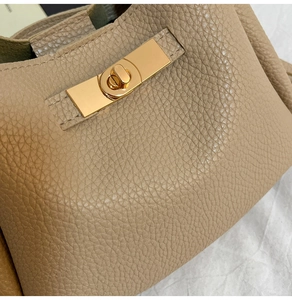 Détail du fermoir rotatif en métal doré sur le sac à main en cuir beige grainé