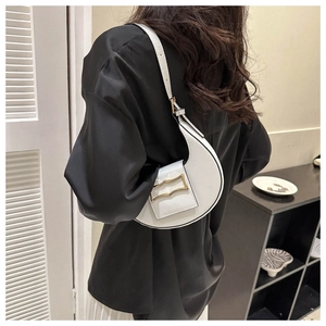 Detail of white leather half-moon hobo bag with gold buckle on model's shoulder