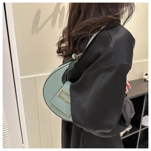Detail of mint green crescent bag with matte leather finish and gold buckle hardware