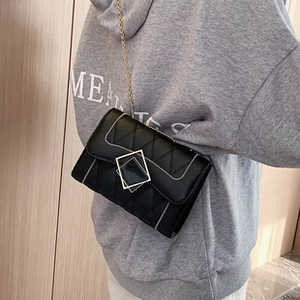 Close-up of black quilted crossbody bag with gold chain strap and square metal buckle