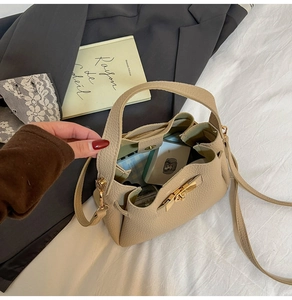Détail d'un sac à main beige en cuir grainé montrant l'intérieur spacieux et le fermoir