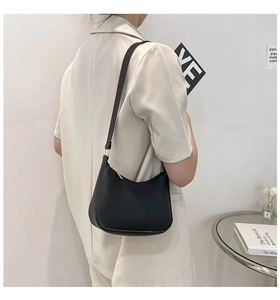 Minimalist black leather hobo shoulder bag with gold zipper shown on a model