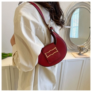 Close-up of red stone pattern shoulder bag with a unique wavy gold metal clasp detail