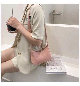 Side view of a pink leather half-moon underarm bag worn by a model in a minimalist style