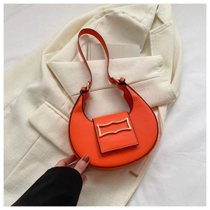 Macro shot of an orange half-moon bag on a white blazer showing texture and gold buckle