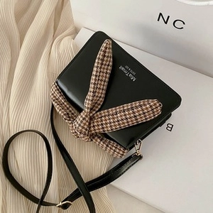 Top view of black crossbody bag with plaid bow and earphone port for outdoor use