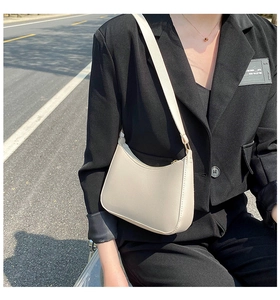 Detail of minimalist beige underarm bag with smooth matte finish and gold hardware