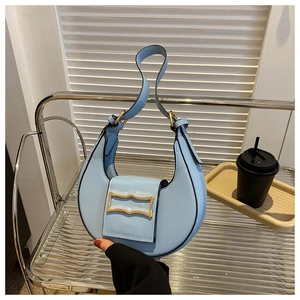 Close-up of light blue crescent bag with vintage gold buckle on a minimalist shelf