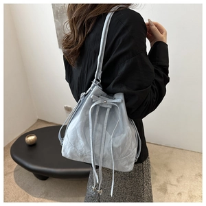 Detail of light blue water-ripple textured bucket bag with drawstring and metal beads