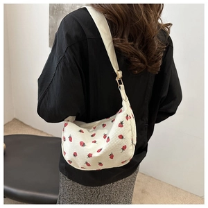 Detail of white corduroy crescent bag with strawberry print and adjustable canvas strap
