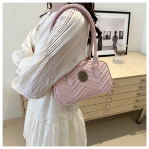 Close-up of pink chevron quilted shoulder bag with vintage gold circular metal logo