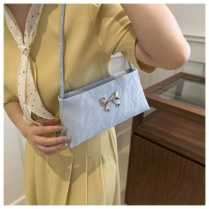 Détail du sac à bandoulière plissé bleu clair avec un nœud en métal argenté