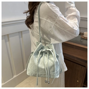 Detail of mint green bucket bag with drawstring and marble texture on white shirt