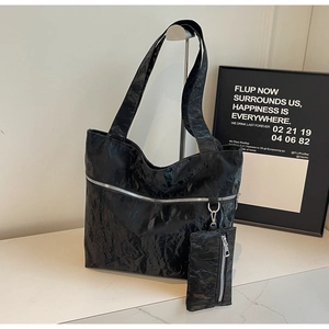 Close-up of black textured tote bag with metal zipper and detachable small coin pouch