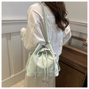 Detail of mint green drawstring bucket bag with silver ball charms and textured finish