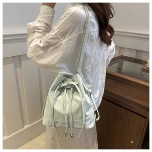 Detail of mint green bucket bag featuring pleated texture and silver drawstring beads