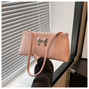 Detail of light pink shoulder bag featuring a silver bow accent and glossy pleated texture