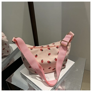 Detail of pink corduroy crescent bag with red strawberry embroidery and wide nylon strap
