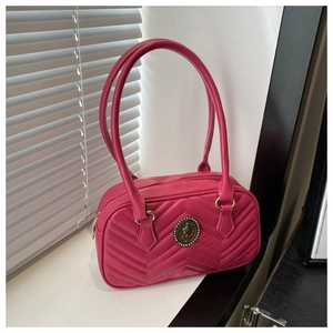 Close-up of fuchsia quilted handbag featuring V-stitch pattern and retro gold logo