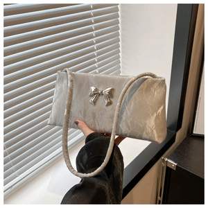 Detail of silver-grey handbag featuring metallic bow hardware and marble-texture fabric