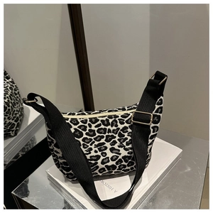 Detail of a black and white leopard print crescent bag with adjustable wide strap and zipper