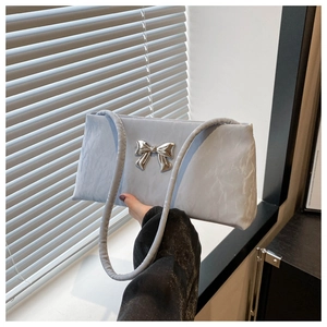 Detail of light blue pleated underarm bag featuring a metallic silver bow and slim strap