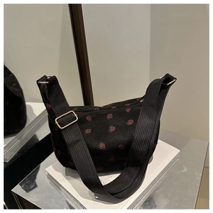 Close-up of black corduroy crescent bag with vibrant red strawberry embroidery