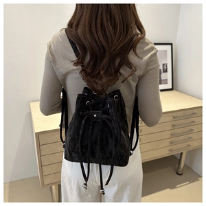 Detail of a black drawstring backpack with bow accent and pleated fabric texture