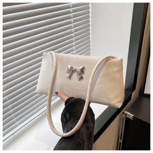 Detail of white square crossbody bag featuring a silver metal bow and cloud texture