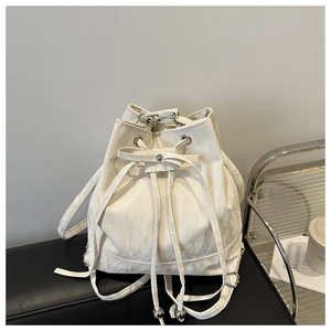 Detail of white pleated drawstring bucket bag with silver eyelets on black leather