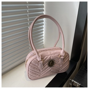 Close-up of pink quilted faux leather shoulder bag with vintage round metal logo detail
