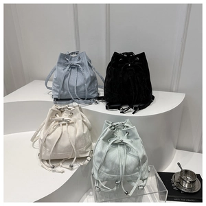 Detail of four colorful drawstring bucket bags with bows in blue, black, white, and green
