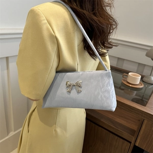 Sac à main bleu clair avec nœud argenté porté par un mannequin en tenue décontractée