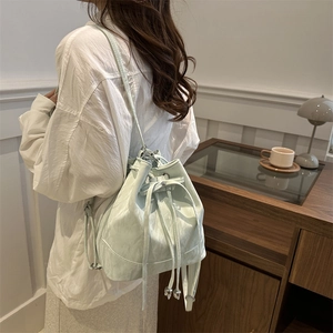 Chic mint green bucket bag with drawstring closure and soft pleated faux leather finish