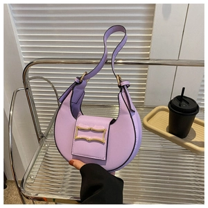 Detail of light purple crescent bag with gold geometric buckle on a modern metal shelf