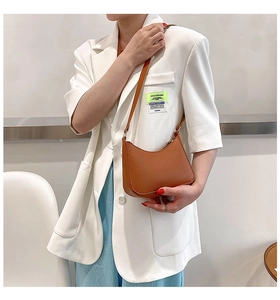 Detailed view of a brown leather hobo shoulder bag worn by a model in a minimal setting