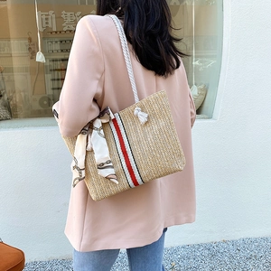 Detailed texture of hand-woven straw tote with cotton rope handle and striped ribbon