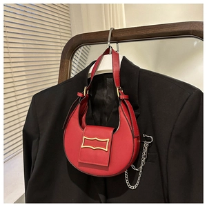Detail view of red crescent bag with gold vintage buckle on a black blazer jacket