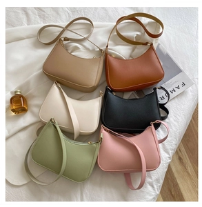 Flat lay of minimalist half-moon bags in six colors on a soft white fabric background