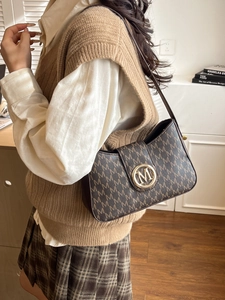 Sac à bandoulière rétro élégant avec monogramme M et boucle dorée sur un mannequin