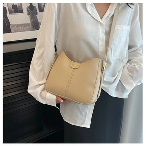 Dettaglio della borsa a tracolla in pelle beige opaca con etichetta Fashion e fibbia in metallo