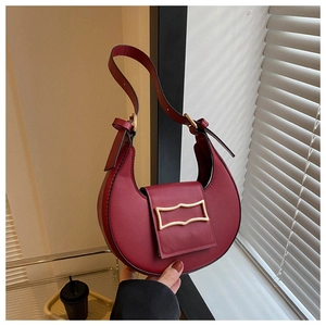 Detail of burgundy stone-patterned hobo bag with golden geometric hardware and flap closure