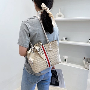 Straw tote bag detail with vertical stripes, rope handles and decorative scarf
