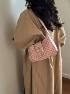 Sac hobo rose avec imprimés lettres M et boucle dorée porté par un mannequin