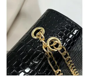 Detail of gold metal chain attachment on black croc-embossed leather crossbody bag