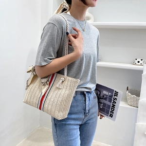 Detail of colorful striped straw tote bag with cotton rope handles and silk scarf accent