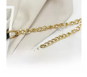 Detailed macro view of a glossy gold metal chain strap on minimalist beige textured fabric