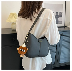 Dettaglio della borsa a spalla vintage nera con ciondolo di peluche su una modella